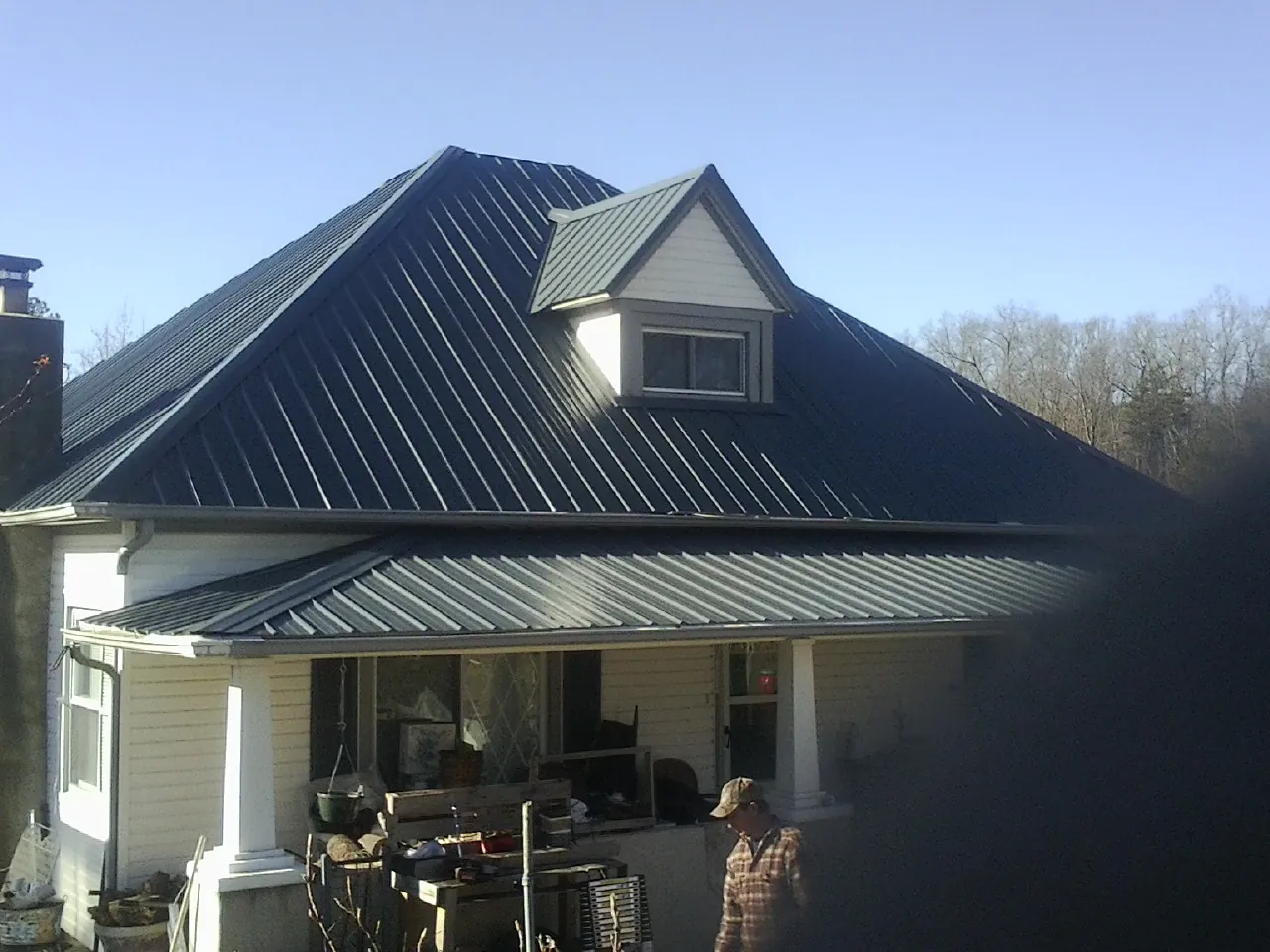 Dark blue standing seam metal roof with a dormer above a front porch in Tolland