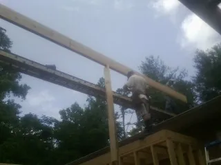 Carpenter setting a ridge beam over a new addition frame — Ice Dam Removal by Roofing Brothers in Tolland