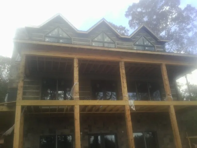Dormers and porch framing on a large log home under construction — Roof Coating work by our crew in Tolland