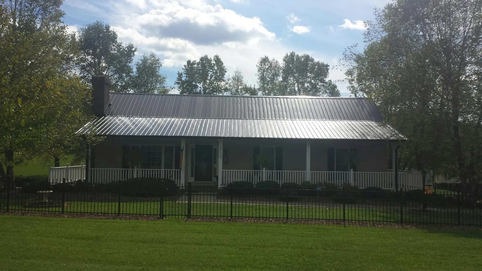 Gray metal roof on a brick ranch with a full width front porch — Gutter Guard Installation work by our crew in Tolland