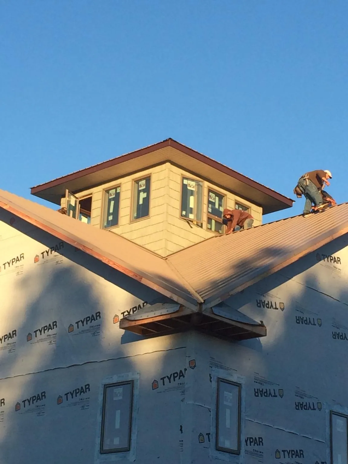 Roofers working around a rooftop cupola on a new metal roof at sunset — Roof Waterproofing in Tolland by Roofing Brothers